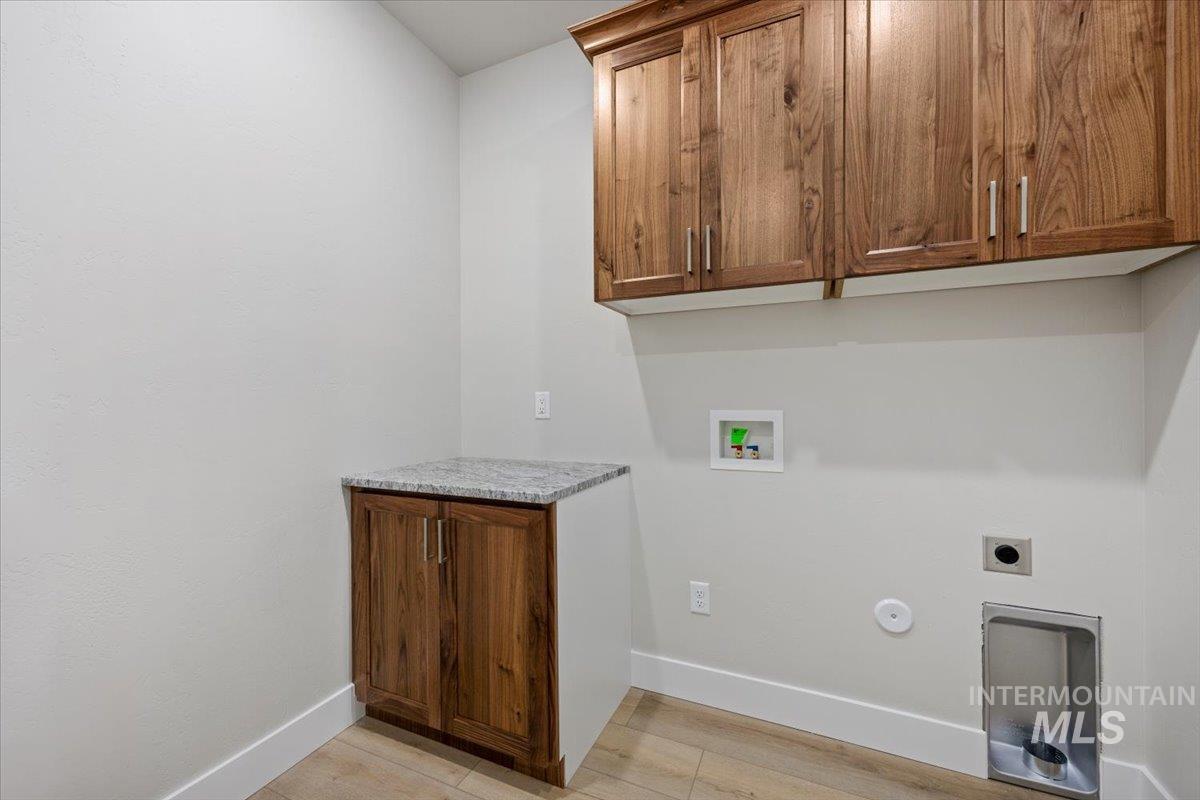 Laundry room featuring light wood-style flooring, washer hookup, electric dryer hookup, cabinet space, and hookup for a gas dryer