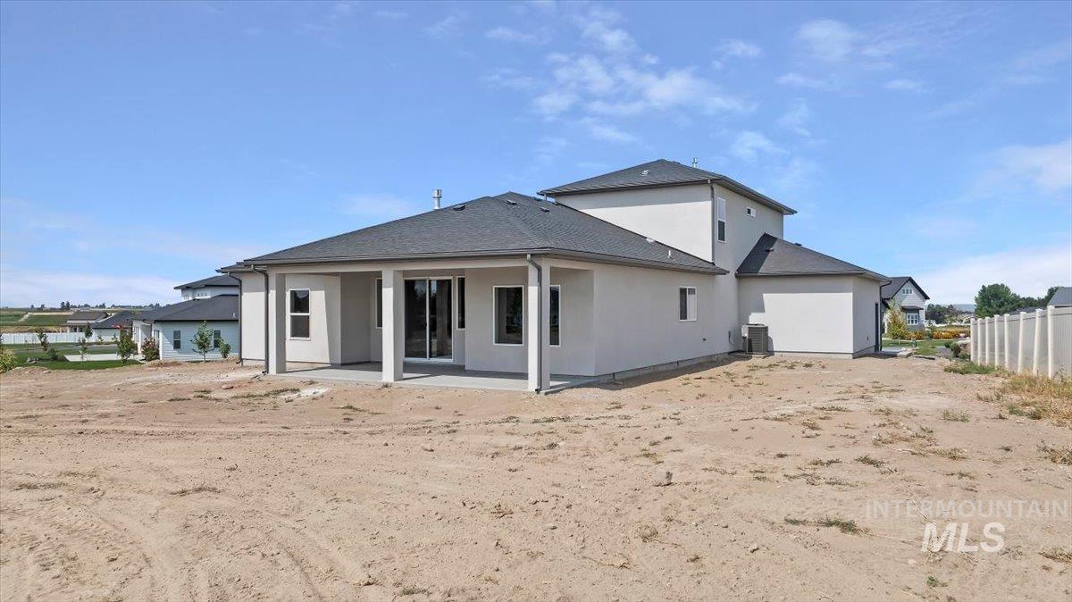 Rear view of property with a patio area, stucco siding, and roof with shingles