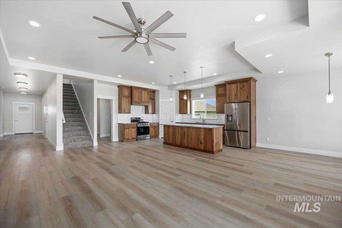Kitchen featuring open floor plan, pendant lighting, stainless steel appliances, tasteful backsplash, and recessed lighting