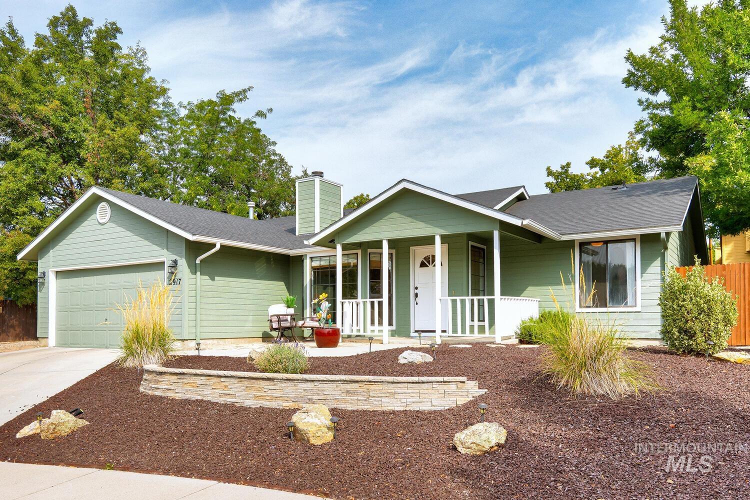 Ranch-style house featuring covered porch, a garage, driveway, a chimney, and a shingled roof
