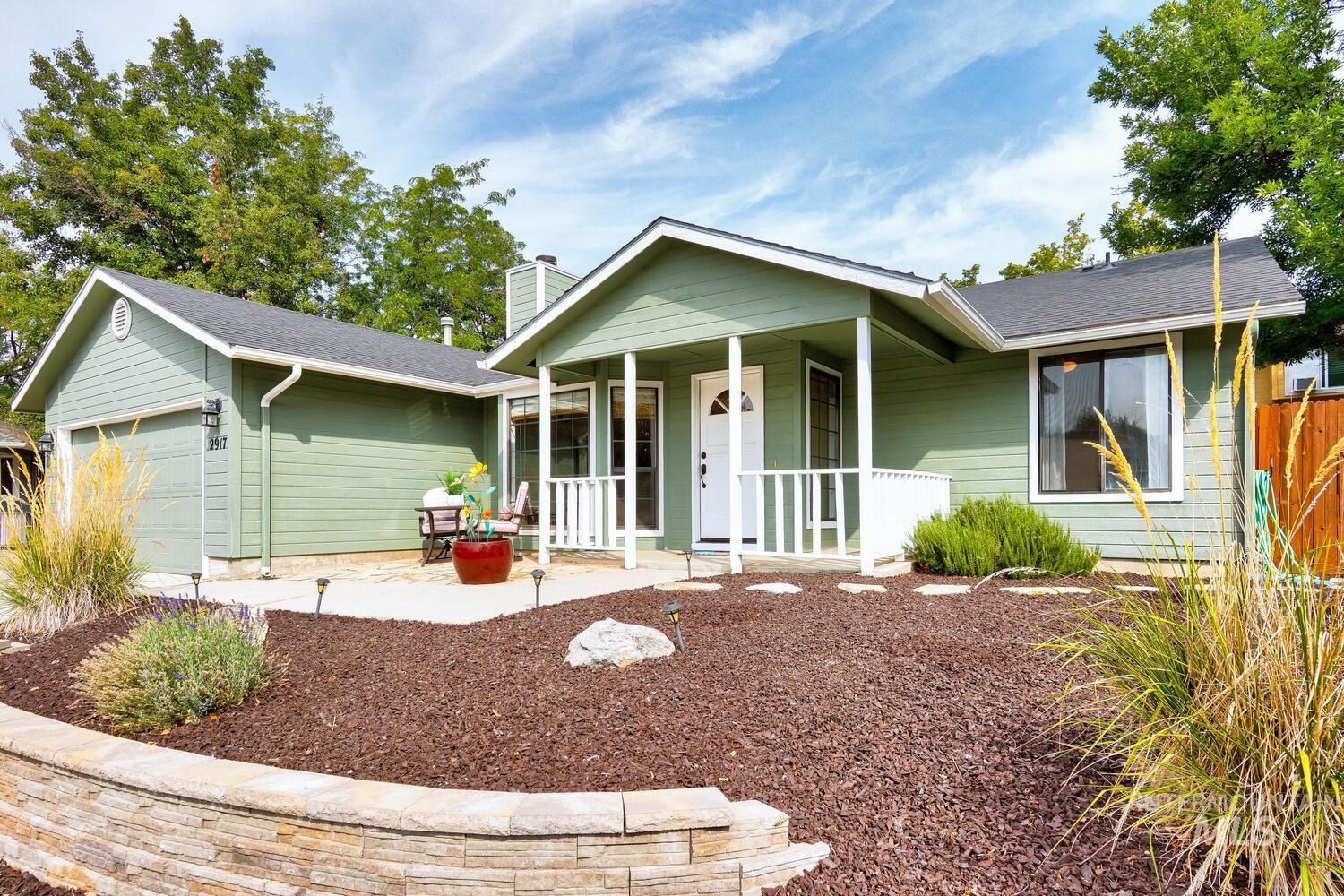 Single story home featuring an attached garage, a porch, a chimney, and a shingled roof