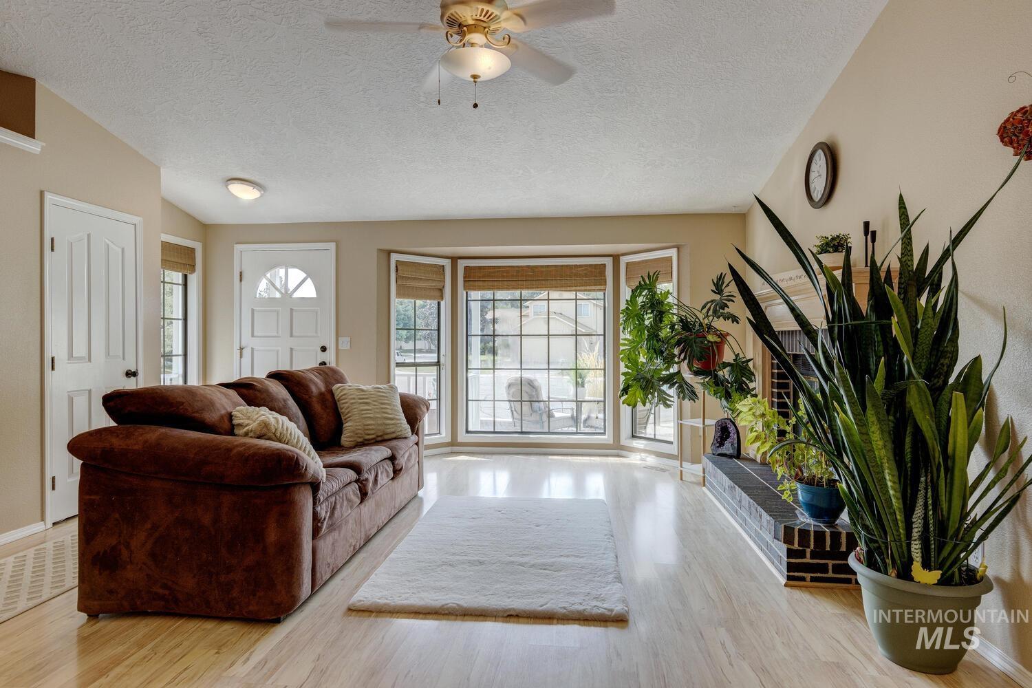Living area featuring a textured ceiling, light wood-type flooring, and ceiling fan