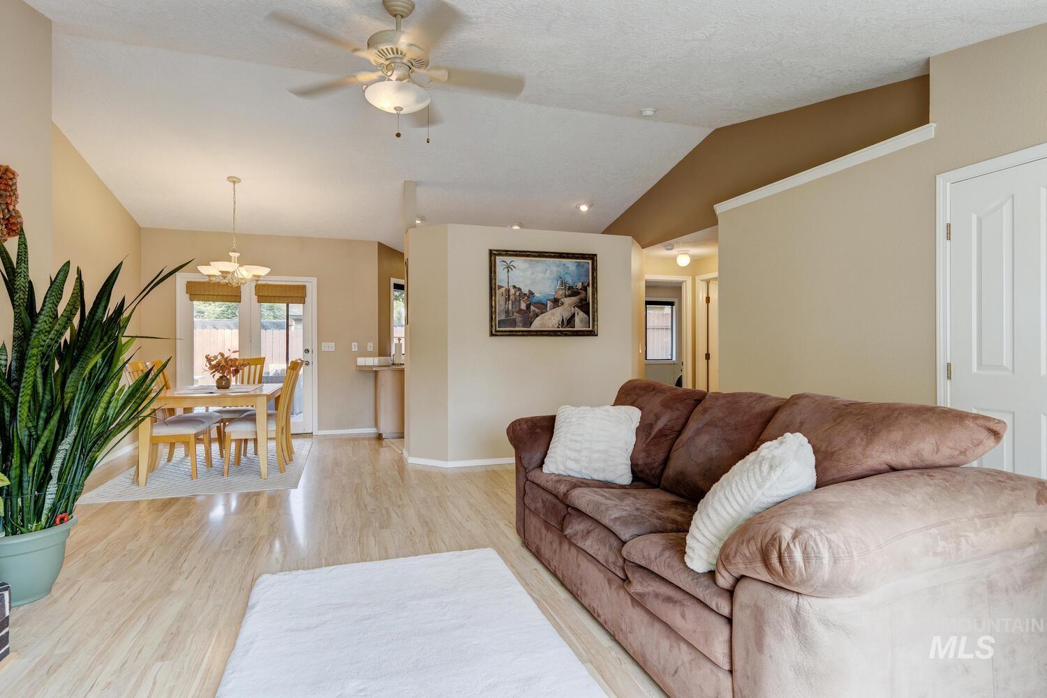 Living area featuring wood finished floors, lofted ceiling, a ceiling fan, and a chandelier