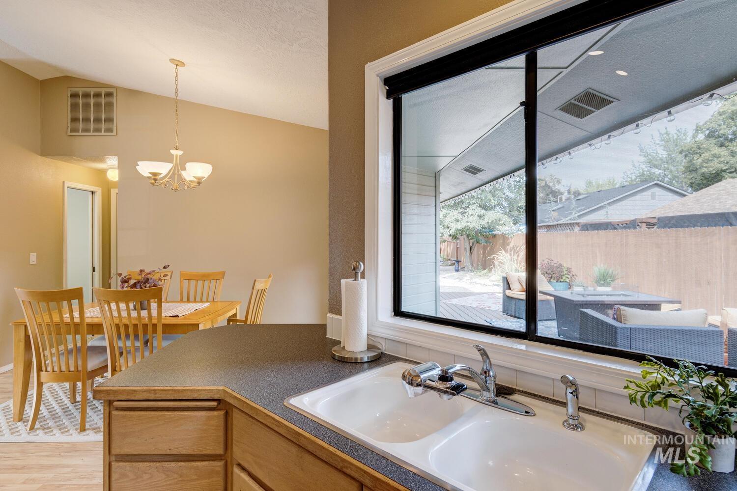 Kitchen featuring dark countertops, lofted ceiling, pendant lighting, light wood-style flooring, and a chandelier