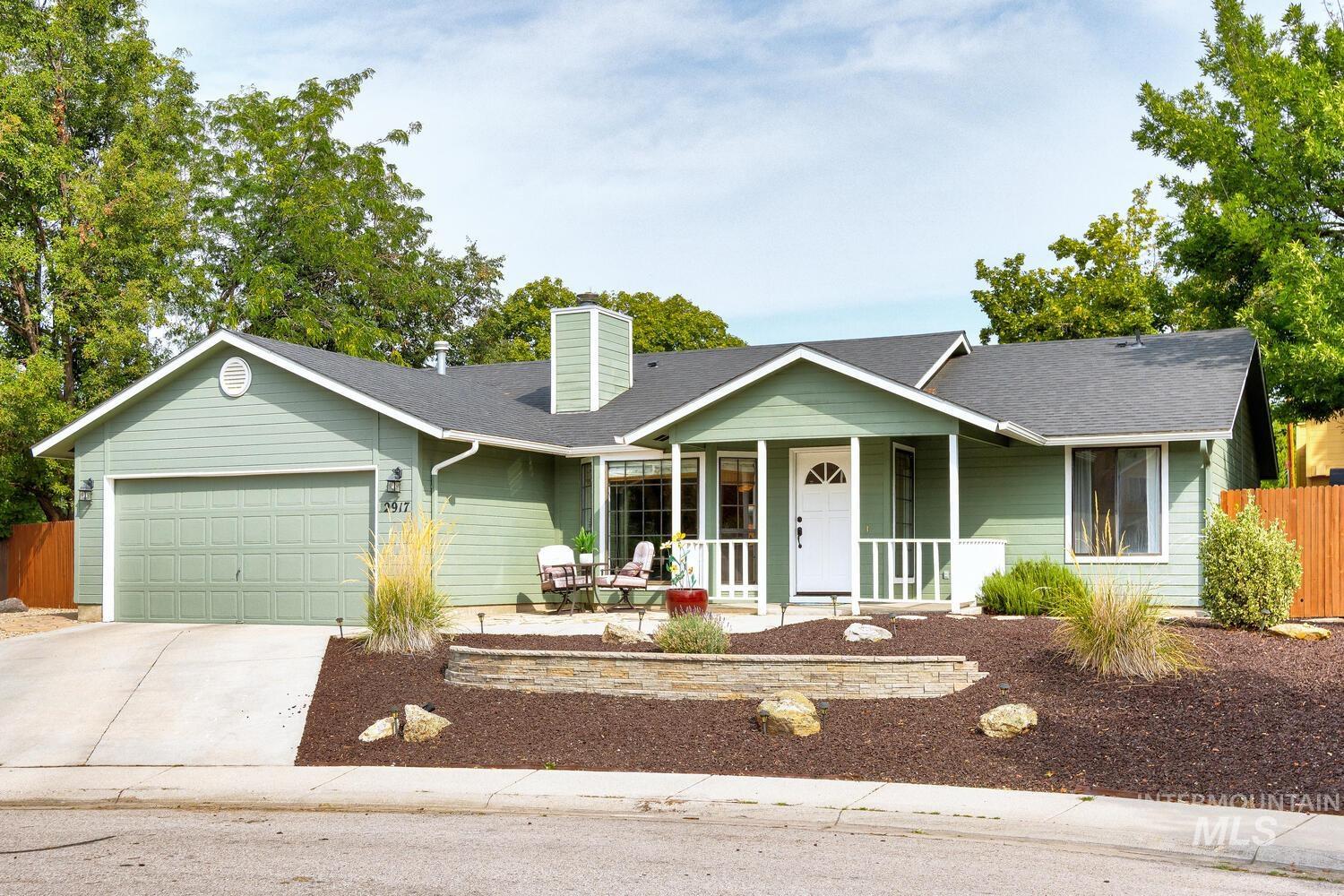 Ranch-style house with covered porch, concrete driveway, a chimney, an attached garage, and a shingled roof