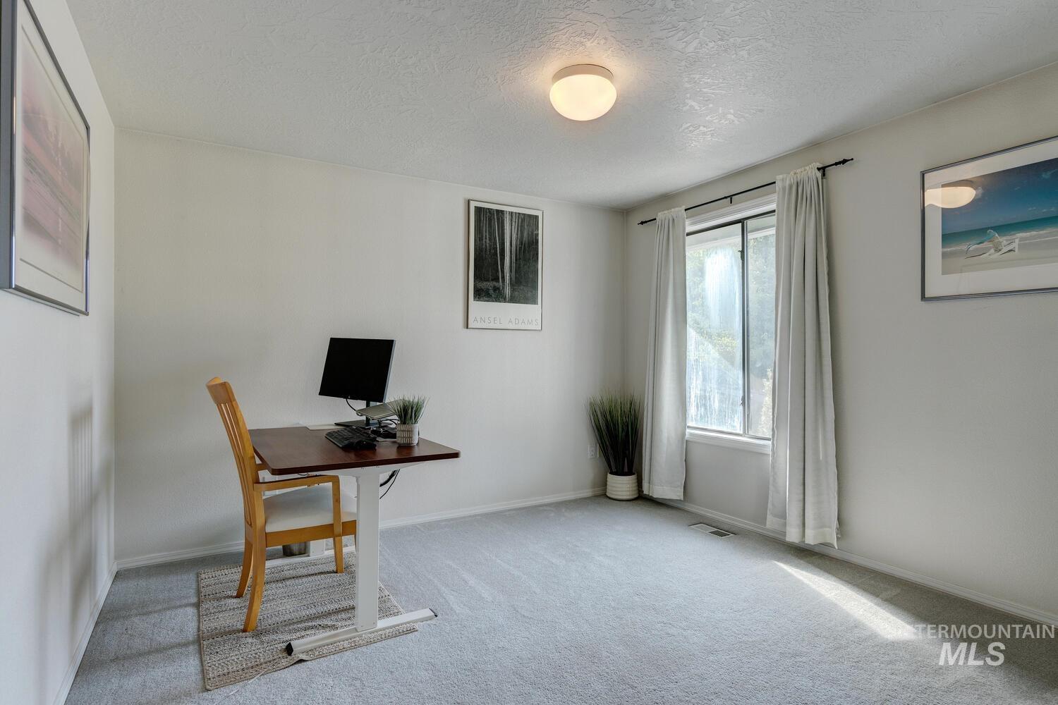 Unfurnished office featuring carpet flooring and a textured ceiling