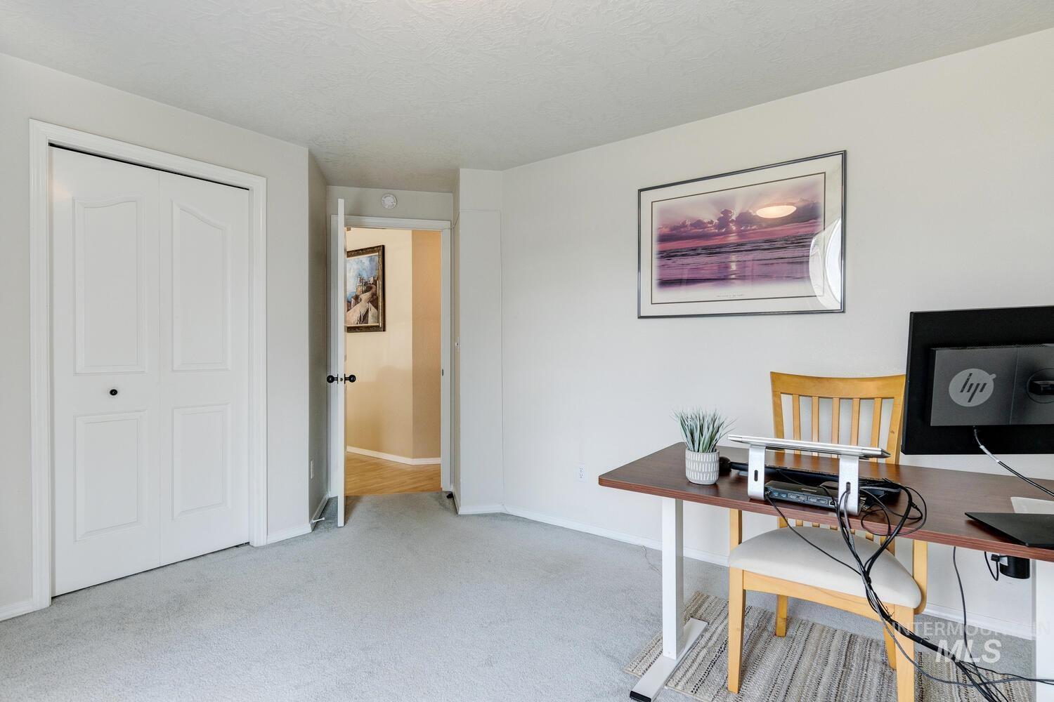 Office area with light colored carpet and a textured ceiling