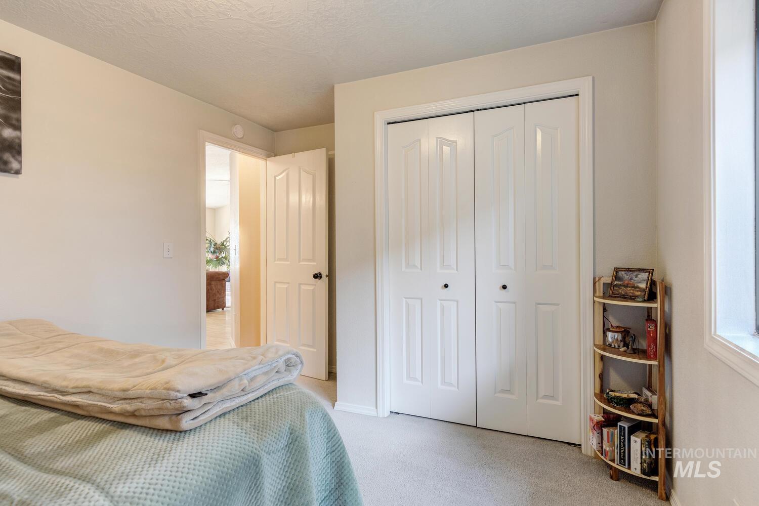 Bedroom with light colored carpet, a closet, and a textured ceiling