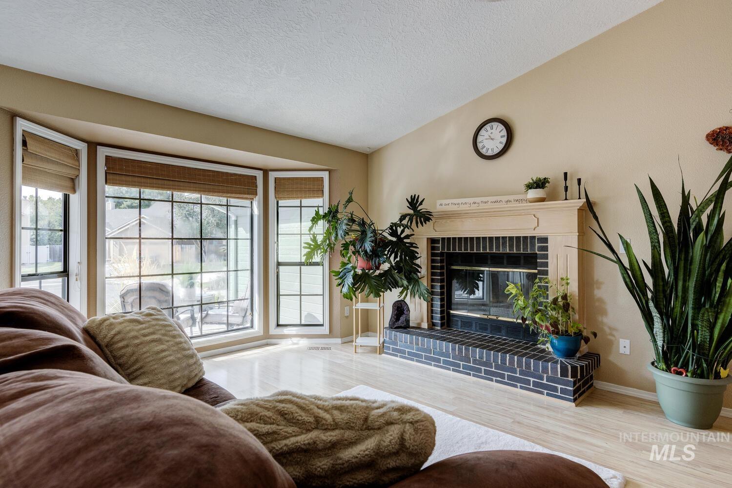 Living area with vaulted ceiling, a fireplace, wood finished floors, and a textured ceiling