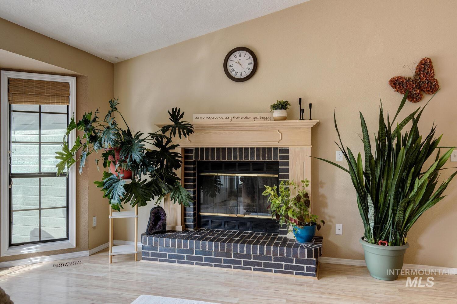 Detailed view of a fireplace, wood finished floors, and a textured ceiling