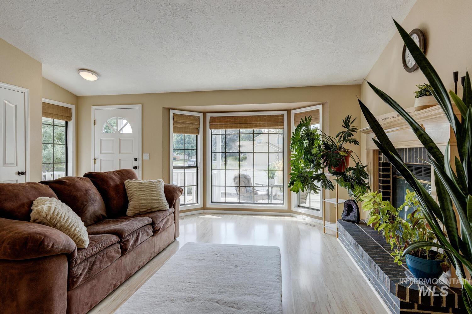 Living room featuring plenty of natural light, a textured ceiling, light wood finished floors, and lofted ceiling