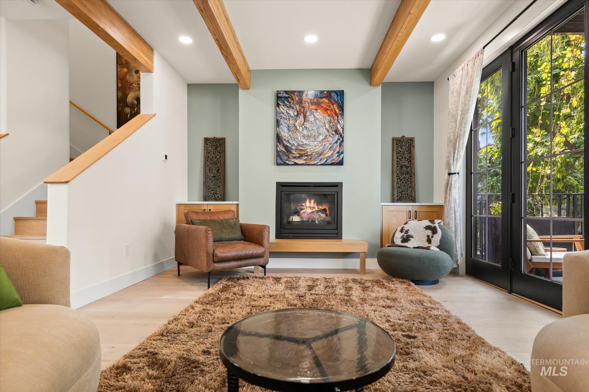 Sitting room with beamed ceiling, stairway, wood finished floors, a glass covered fireplace, and recessed lighting
