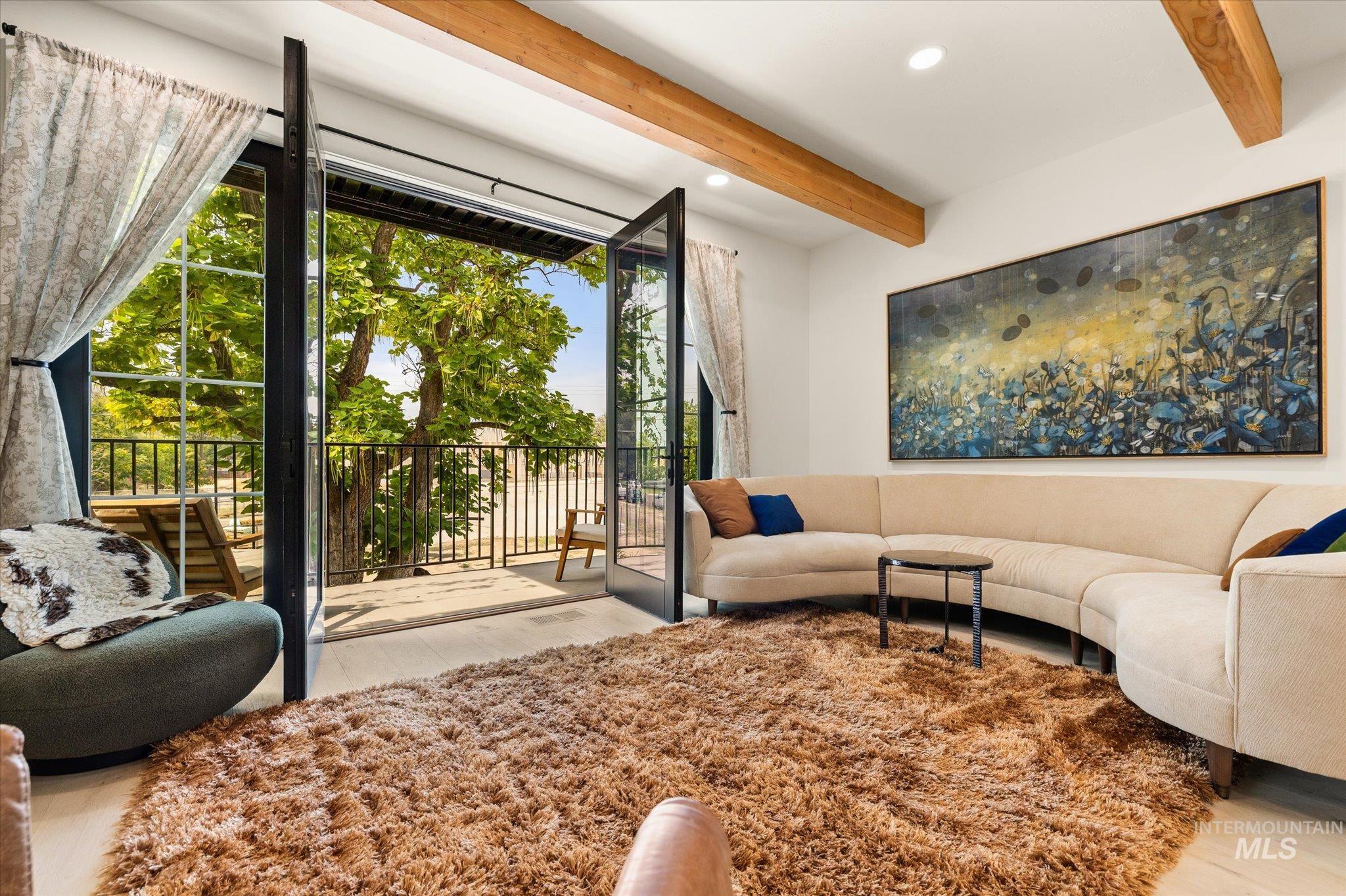 Living room with beamed ceiling, light wood-style flooring, and recessed lighting