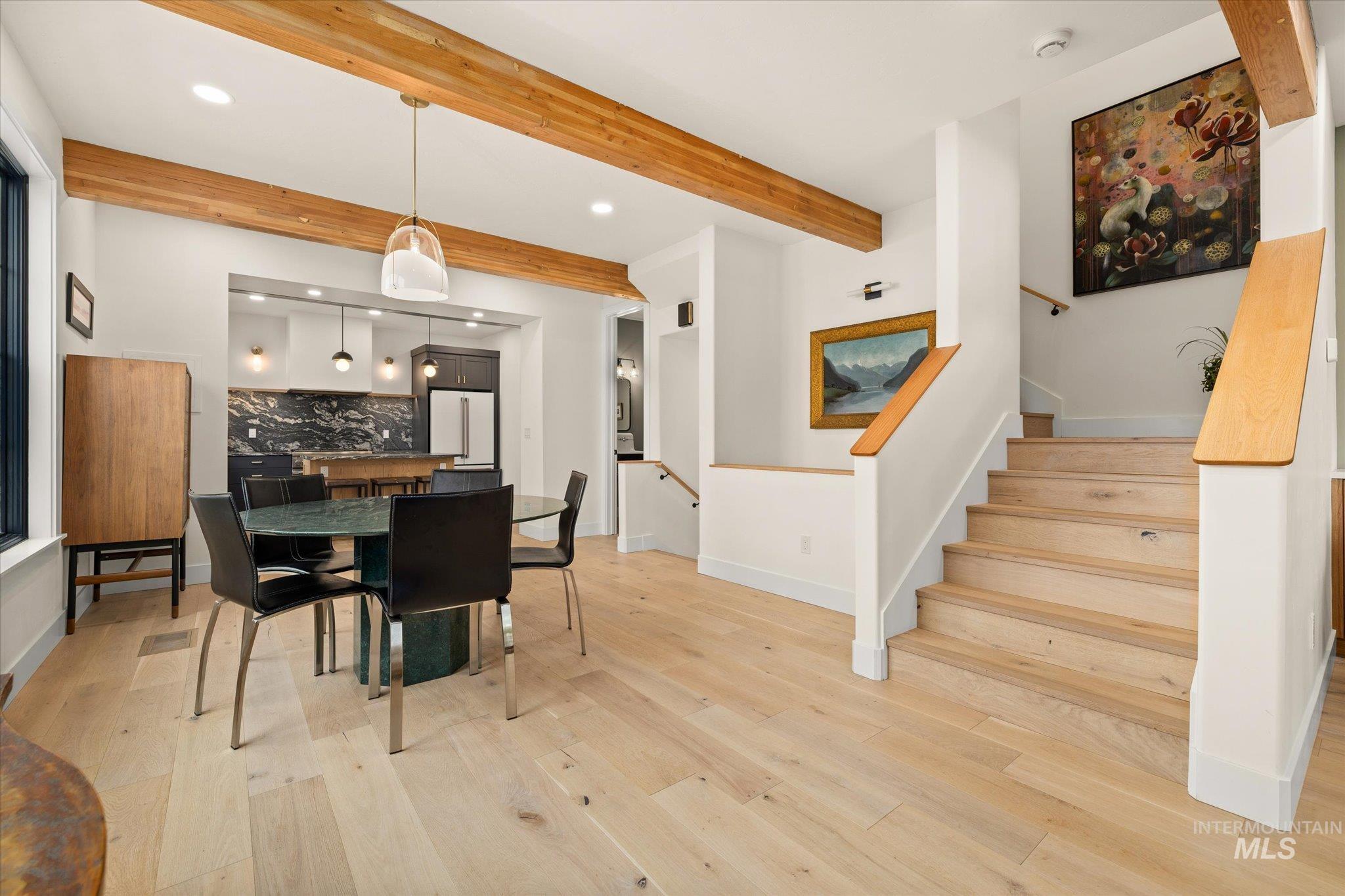 Dining area with beam ceiling, light wood-type flooring, stairway, and recessed lighting