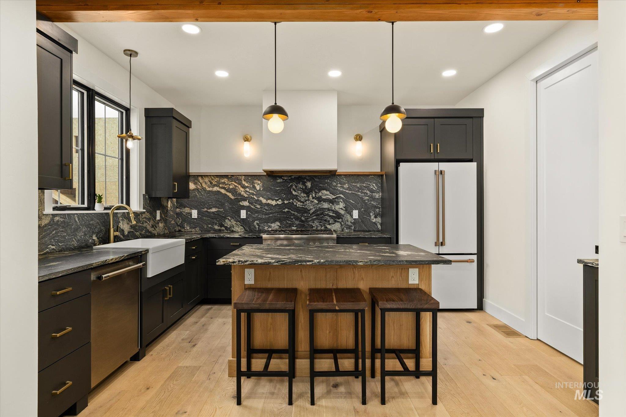 Kitchen with freestanding refrigerator, a kitchen island, a kitchen breakfast bar, hanging light fixtures, and light wood finished floors