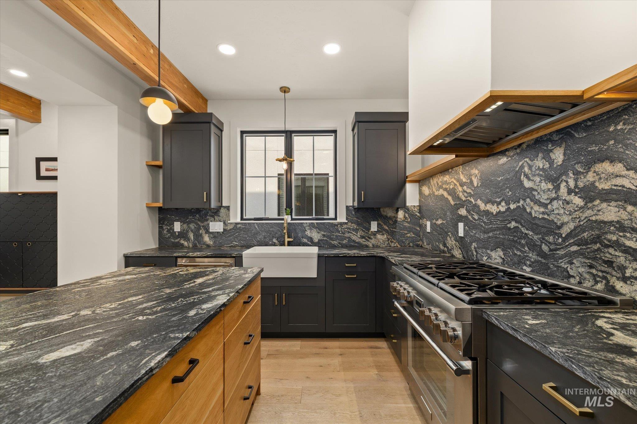Kitchen featuring open shelves, dark stone counters, decorative light fixtures, stainless steel range, and decorative backsplash