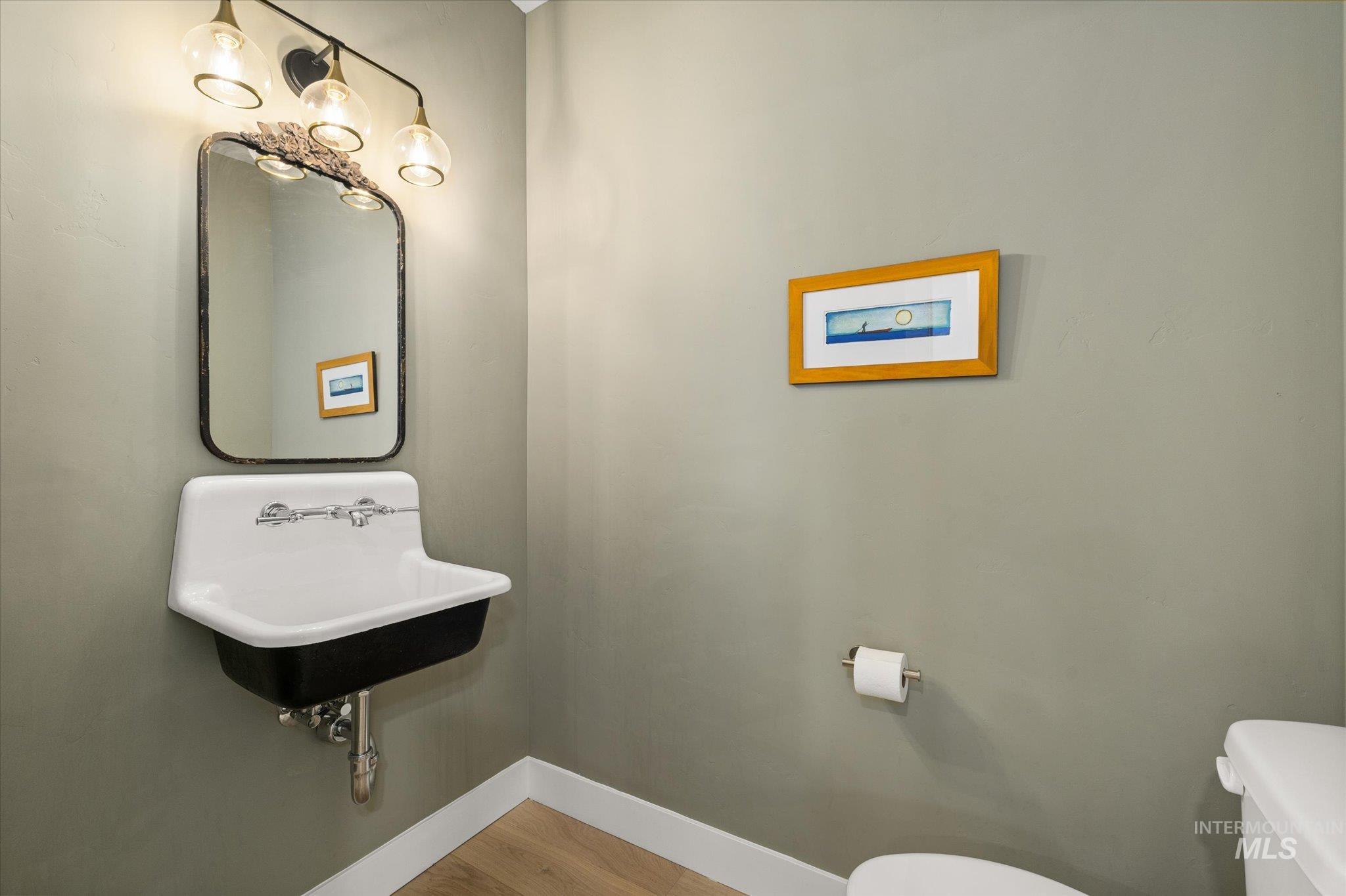 Half bathroom with toilet and wood finished floors