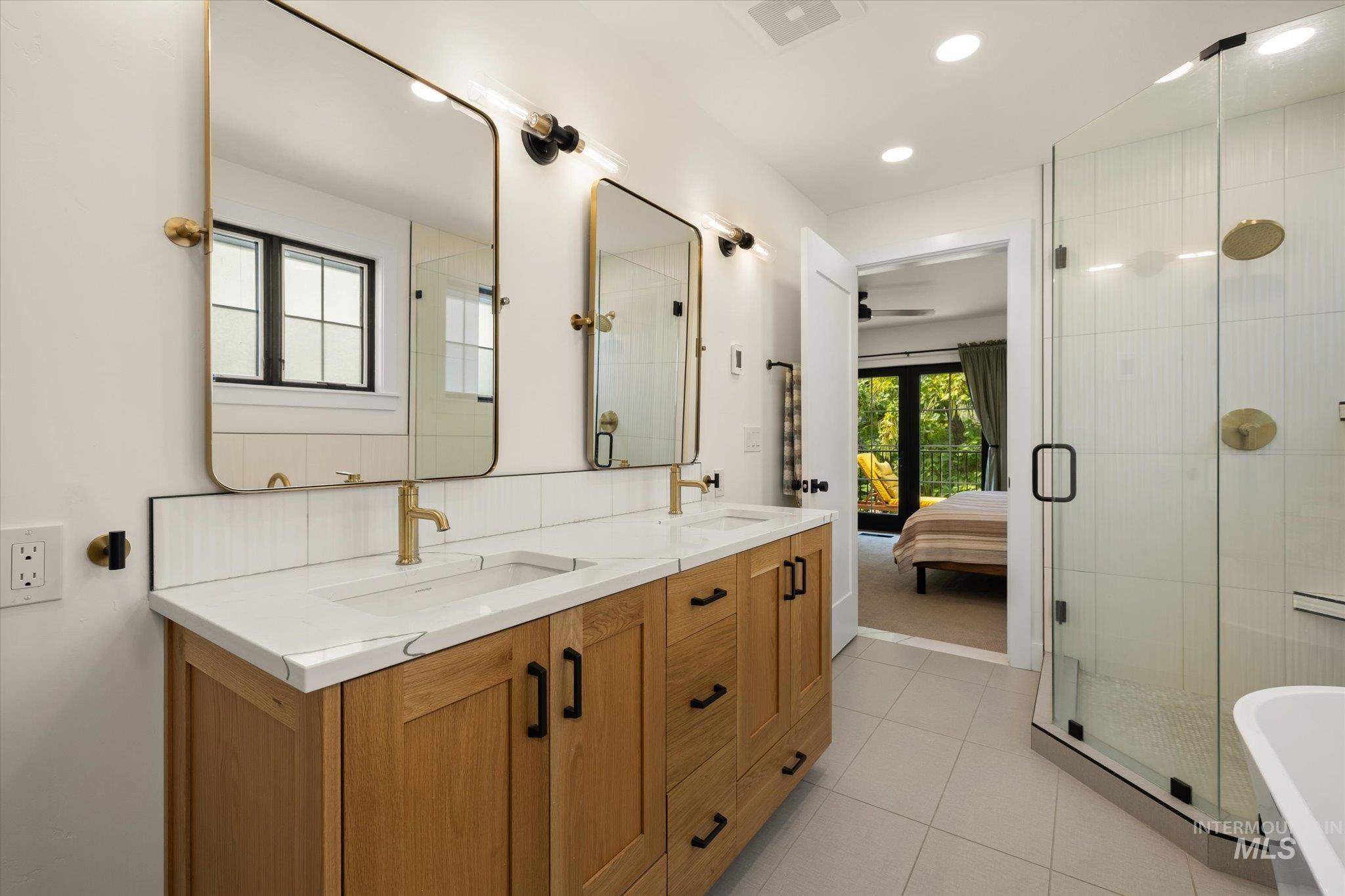 Ensuite bathroom featuring a stall shower, double vanity, light tile patterned floors, recessed lighting, and a freestanding bath