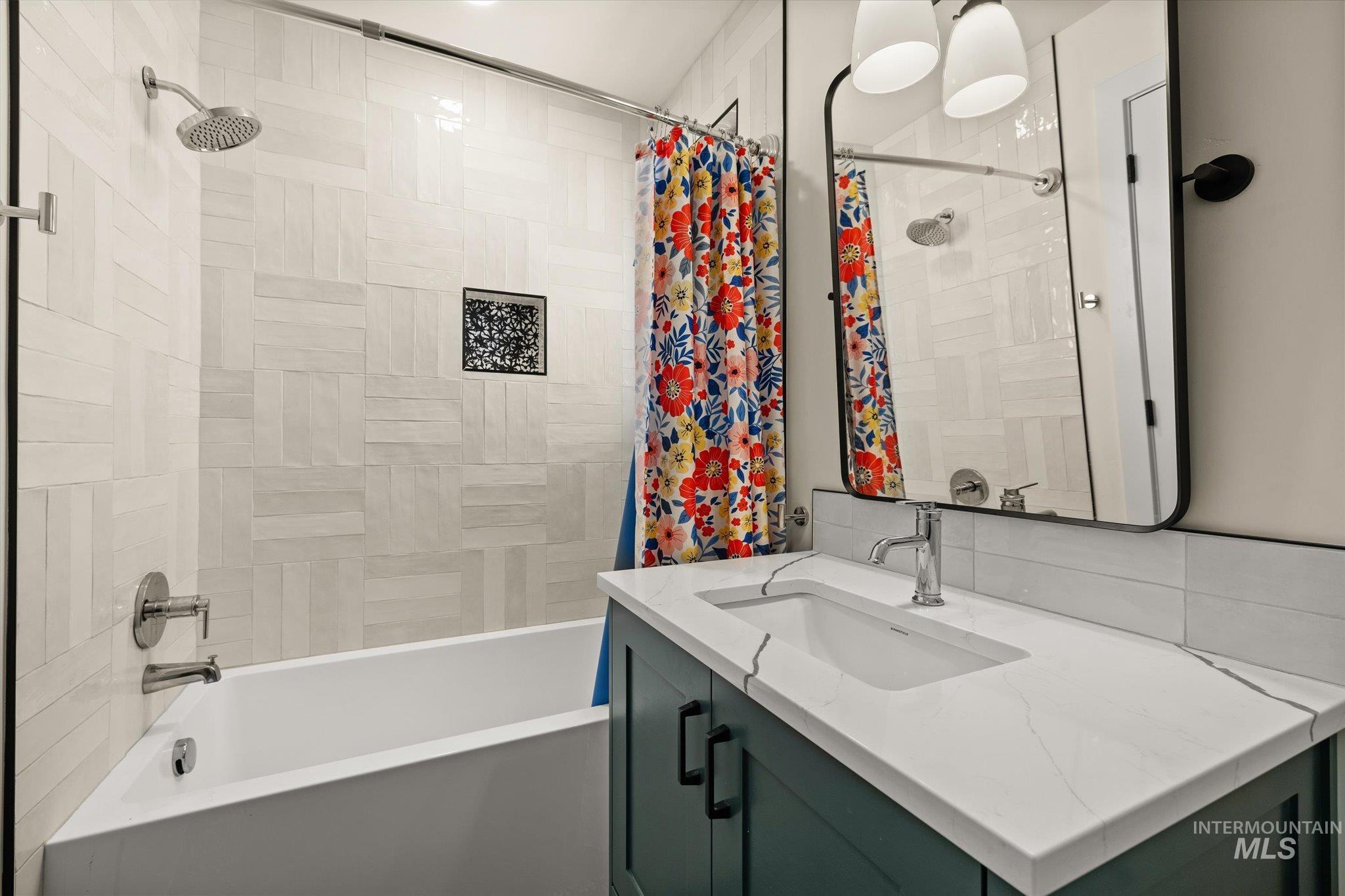 Bathroom featuring shower / bath combination with curtain, vanity, and decorative backsplash