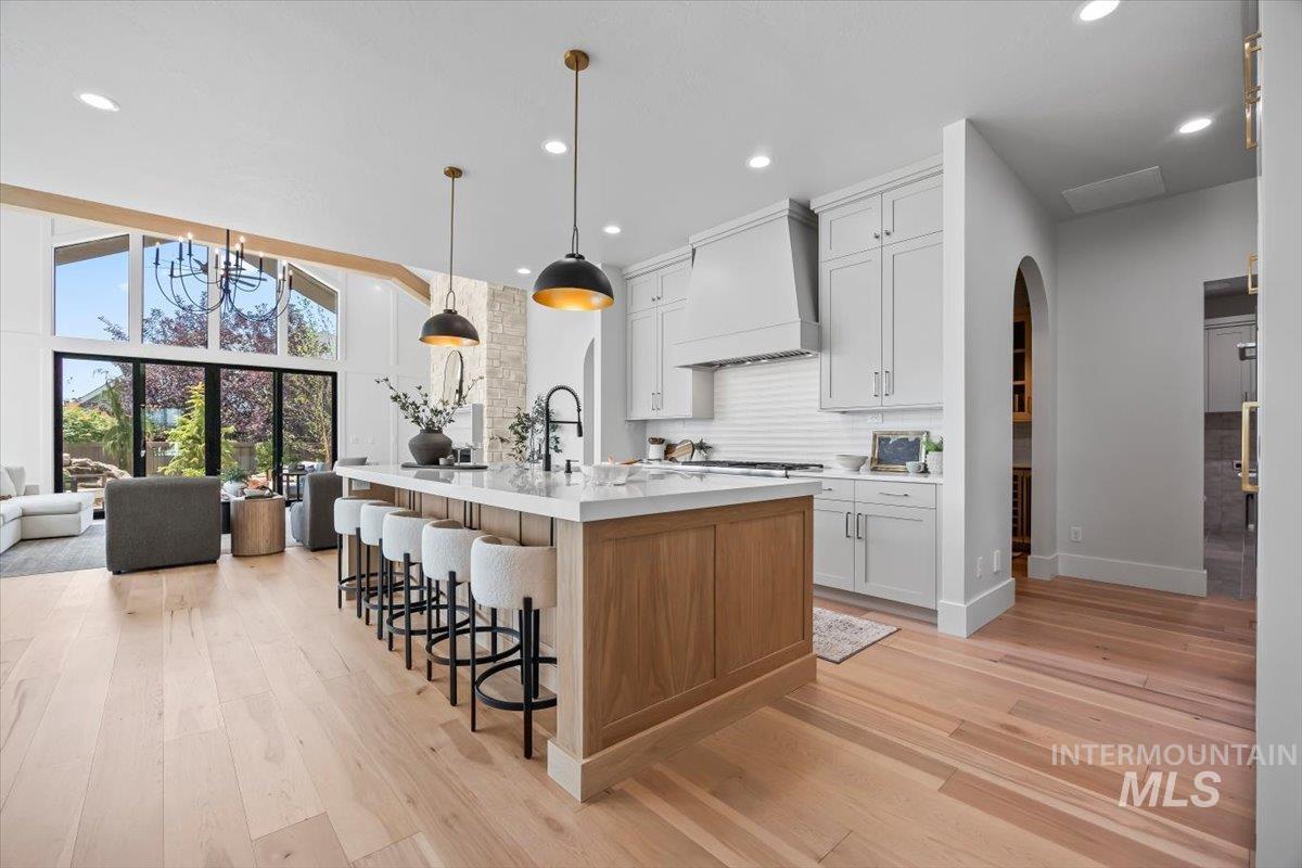 Kitchen featuring light wood-style floors, arched walkways, light countertops, a breakfast bar, and recessed lighting