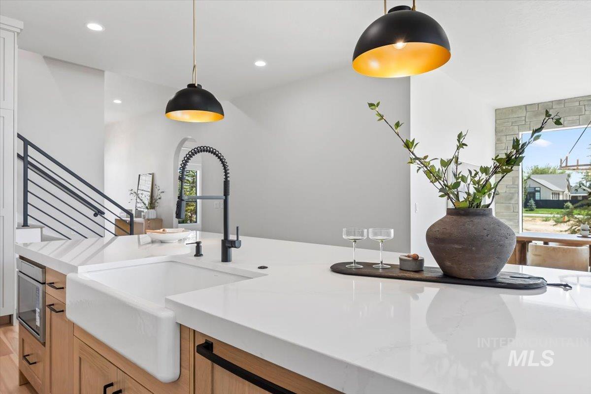 Kitchen featuring light countertops, pendant lighting, and stainless steel microwave