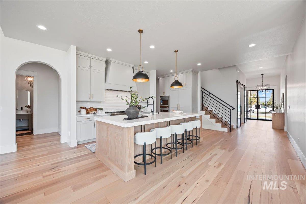Kitchen with a chandelier, light countertops, a kitchen island with sink, a breakfast bar area, and arched walkways