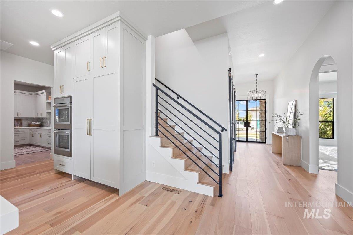 Stairs featuring recessed lighting, wood finished floors, arched walkways, and a chandelier
