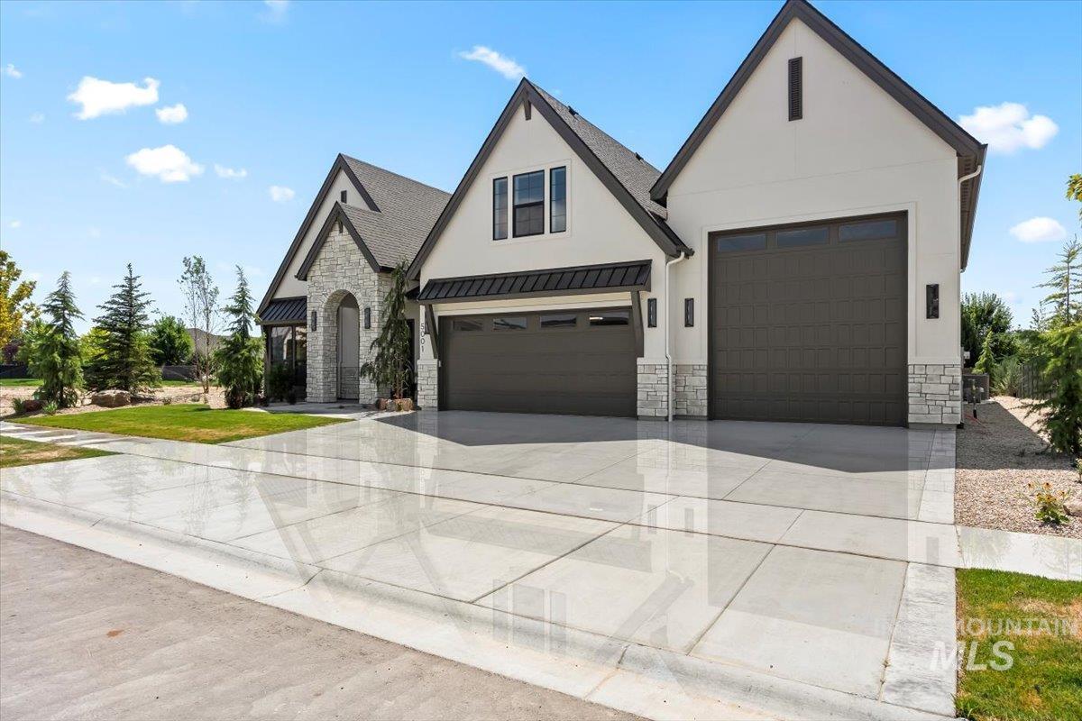 View of front of home featuring stone siding, concrete driveway, a standing seam roof, stucco siding, and a metal roof