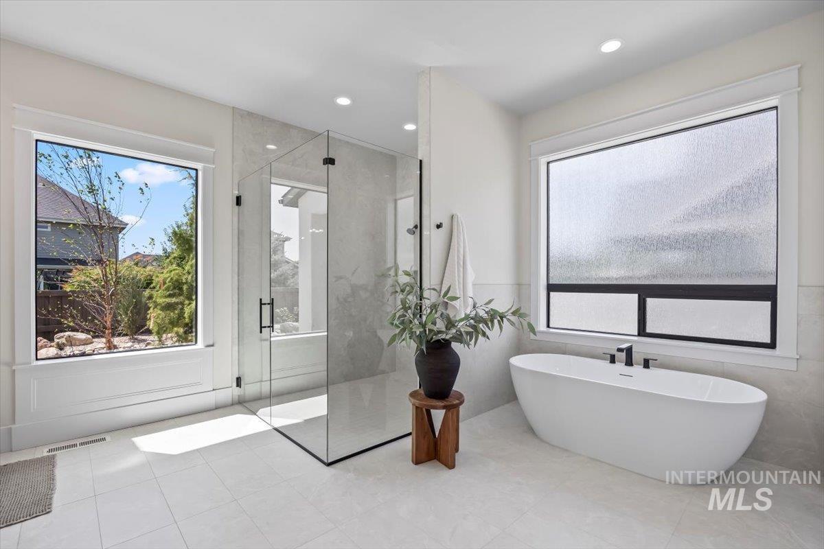 Bathroom with a shower stall, a freestanding bath, tile walls, recessed lighting, and tile patterned flooring