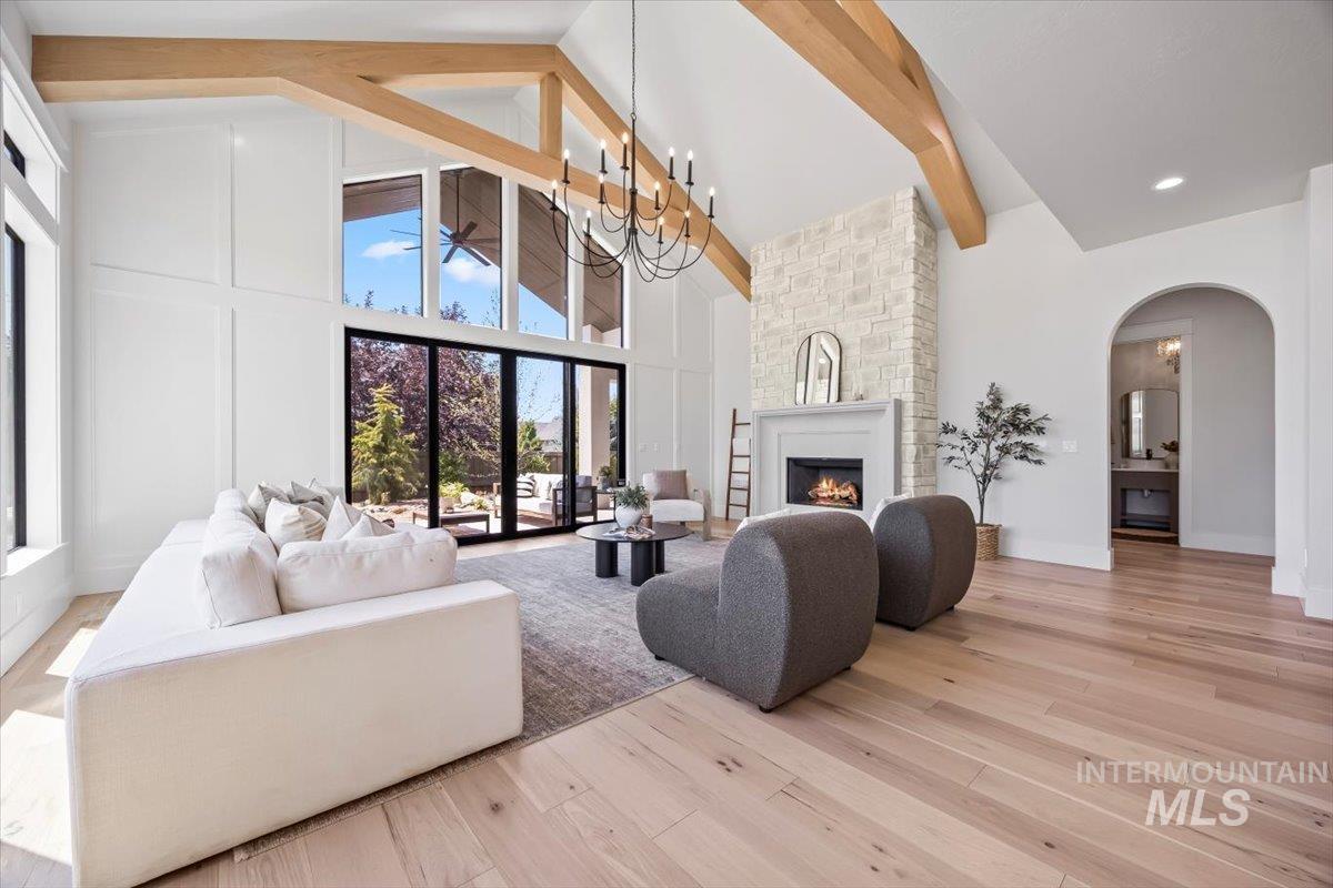Living room featuring a fireplace, light wood finished floors, beamed ceiling, high vaulted ceiling, and arched walkways