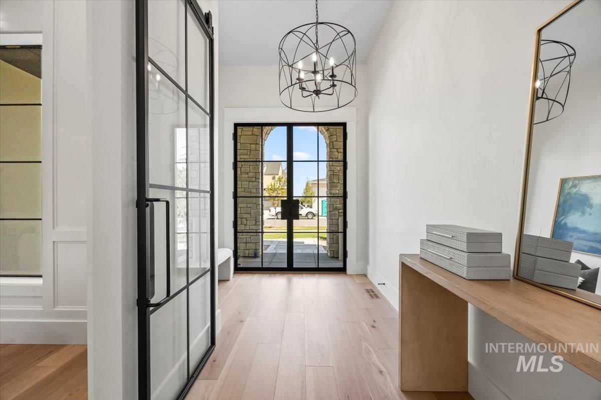 Doorway to outside featuring light wood-type flooring and a chandelier