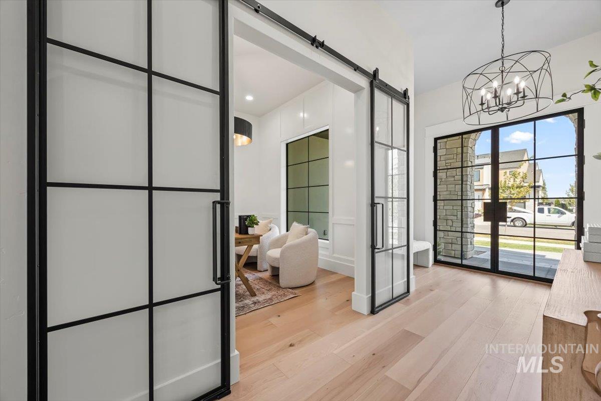 Doorway to outside with a barn door, light wood-style flooring, a chandelier, and french doors