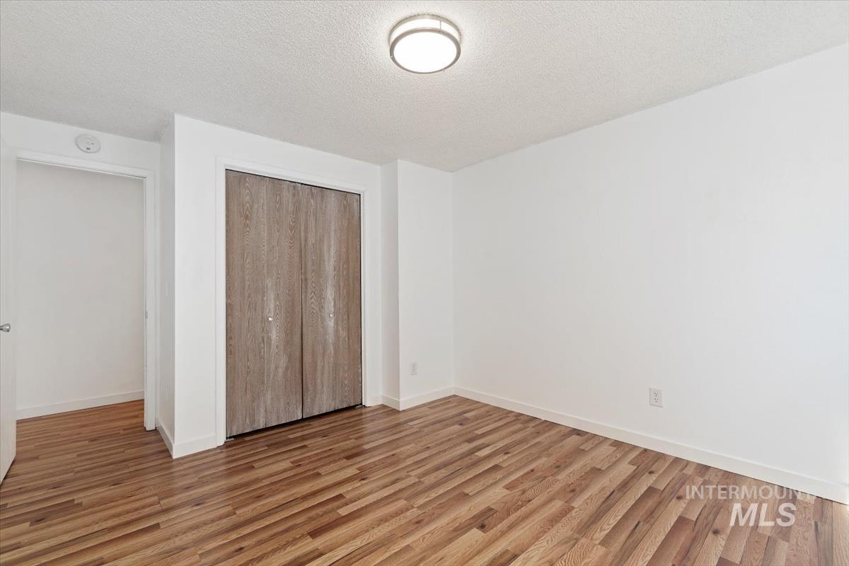 Unfurnished bedroom featuring wood finished floors, a textured ceiling, and a closet