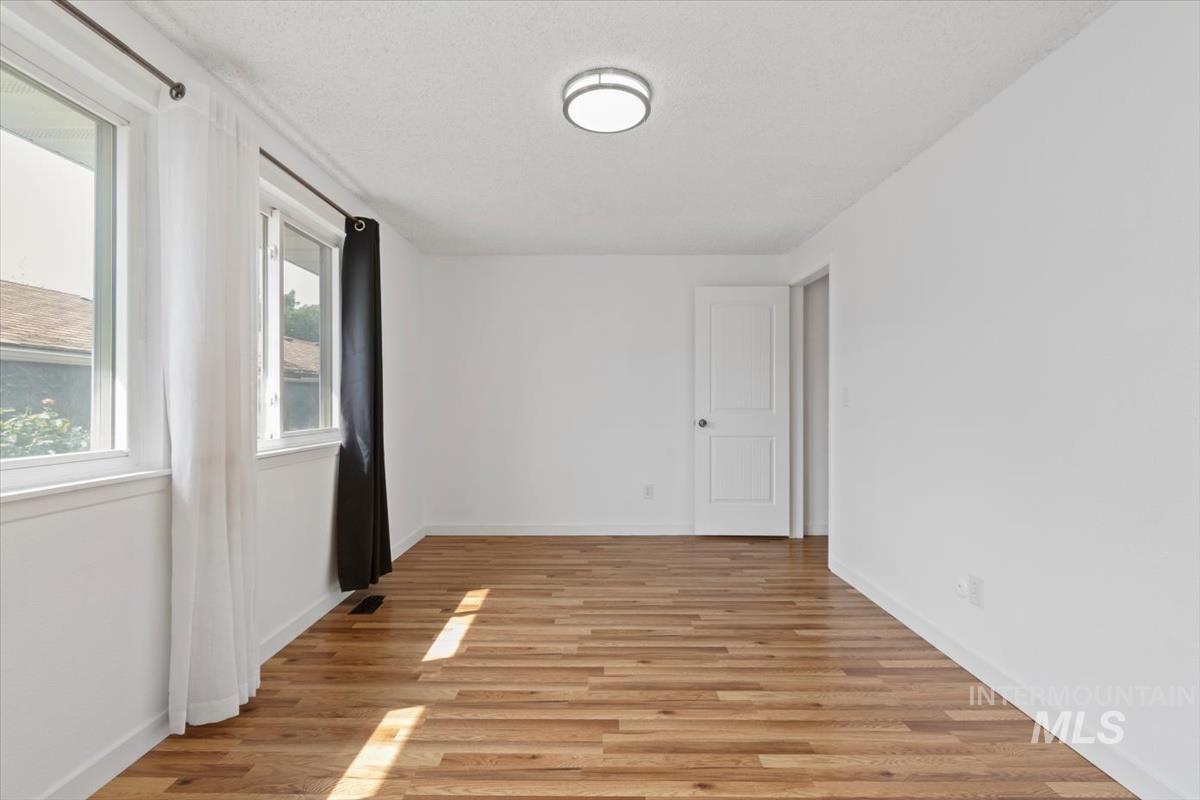 Unfurnished room featuring light wood-style flooring and a textured ceiling