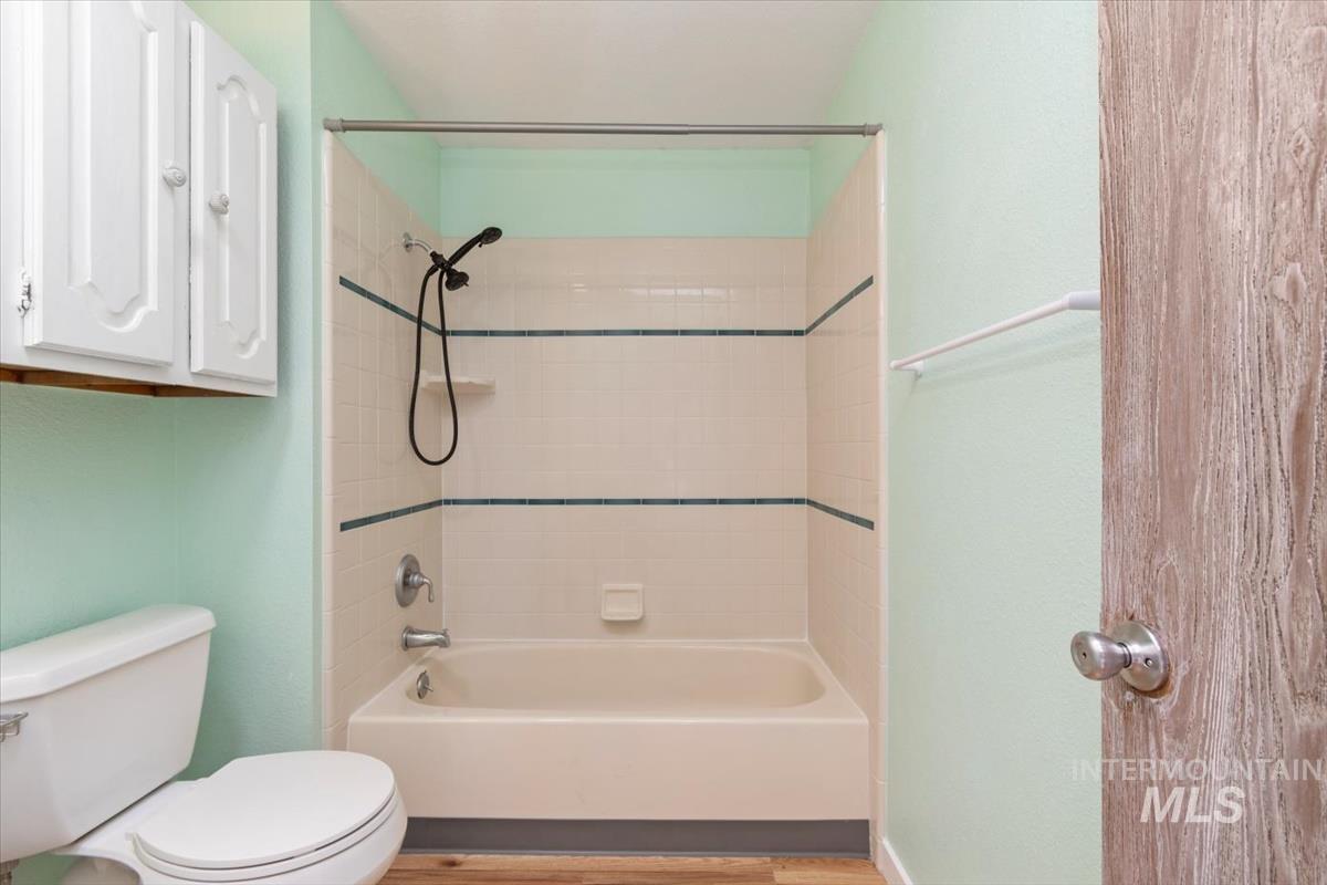 Bathroom with shower / bath combination and light wood-type flooring