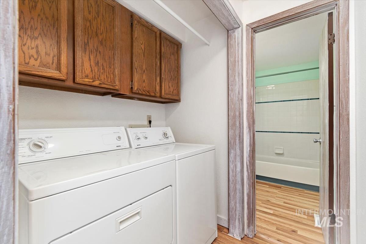 Laundry area featuring cabinet space, light wood-style floors, and independent washer and dryer