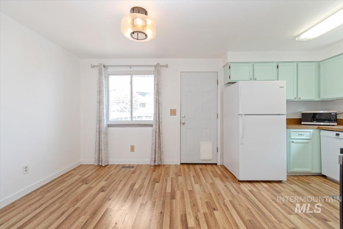 Kitchen featuring white appliances, light wood finished floors, and green cabinets