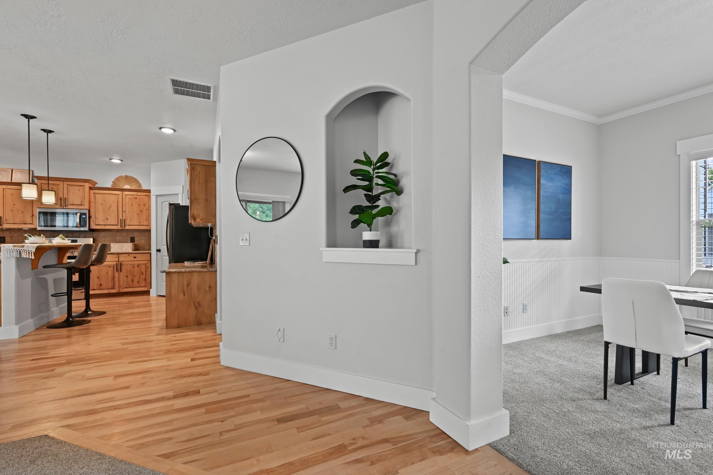 Living room featuring light wood finished floors, ornamental molding, and light colored carpet