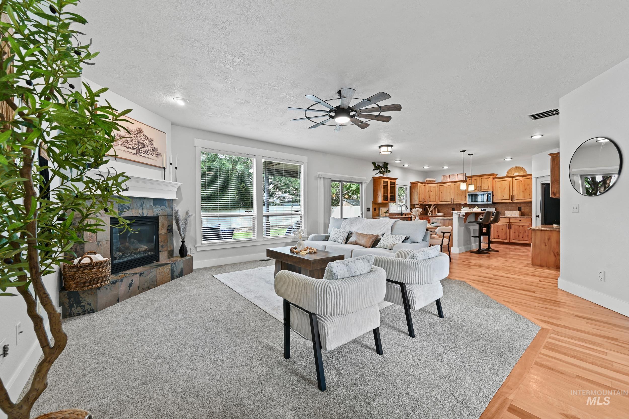 Living area with a tiled fireplace, light wood-style floors, a ceiling fan, and recessed lighting