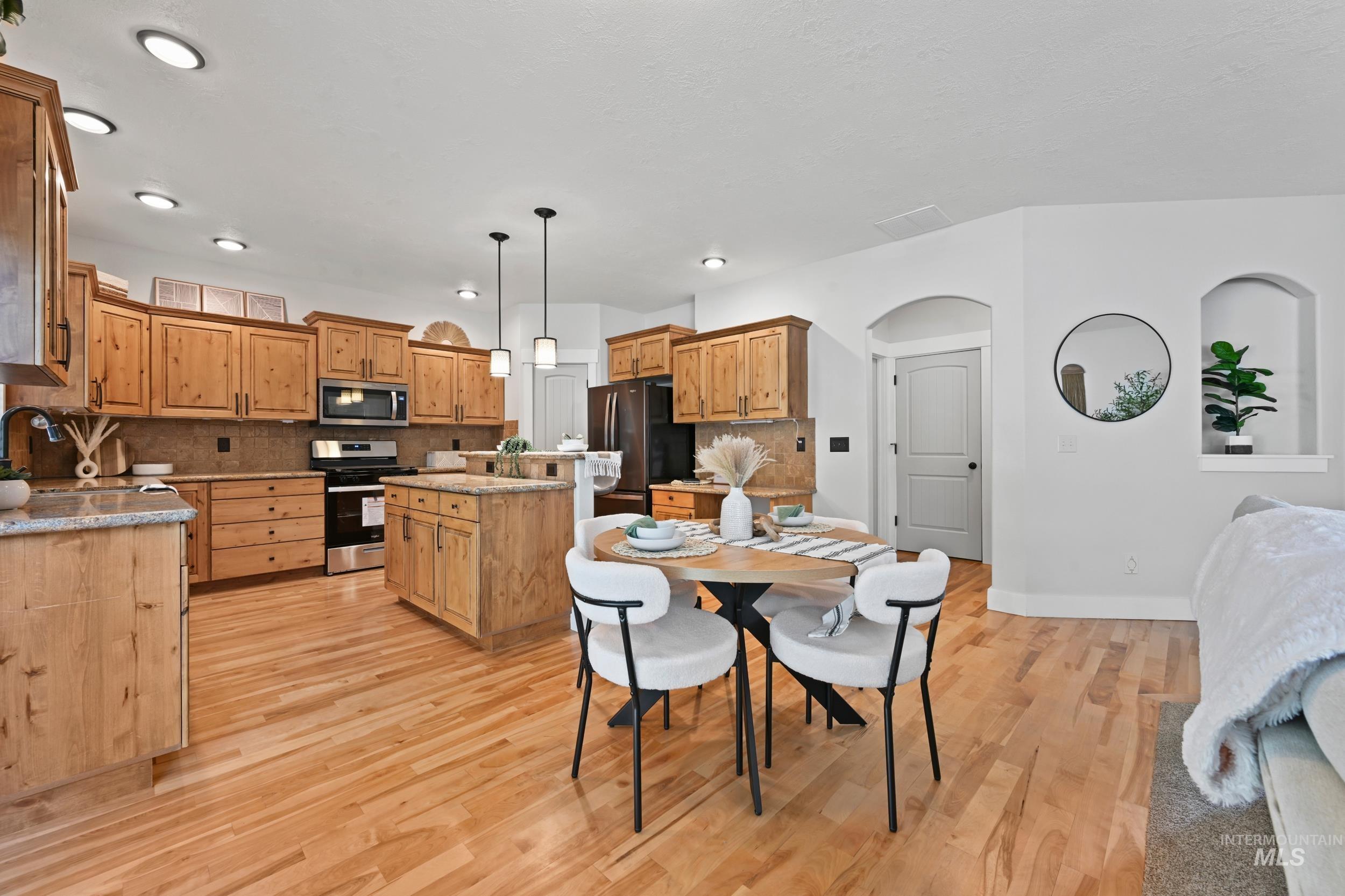 Dining area featuring light wood finished floors, arched walkways, and recessed lighting
