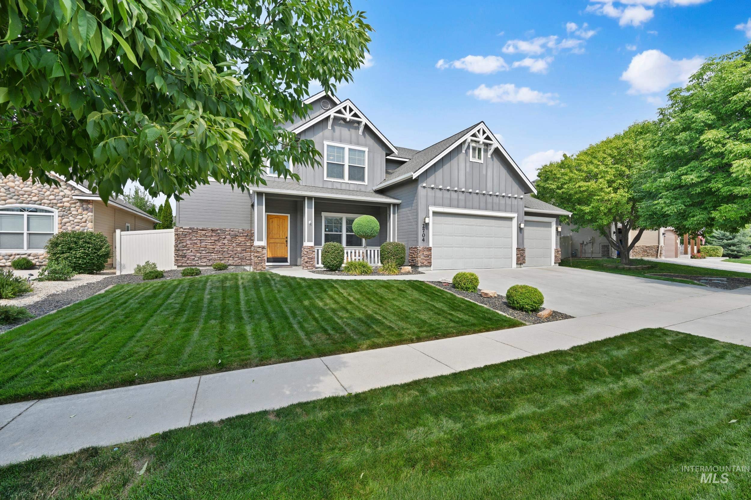 Craftsman-style house with board and batten siding, stone siding, and driveway