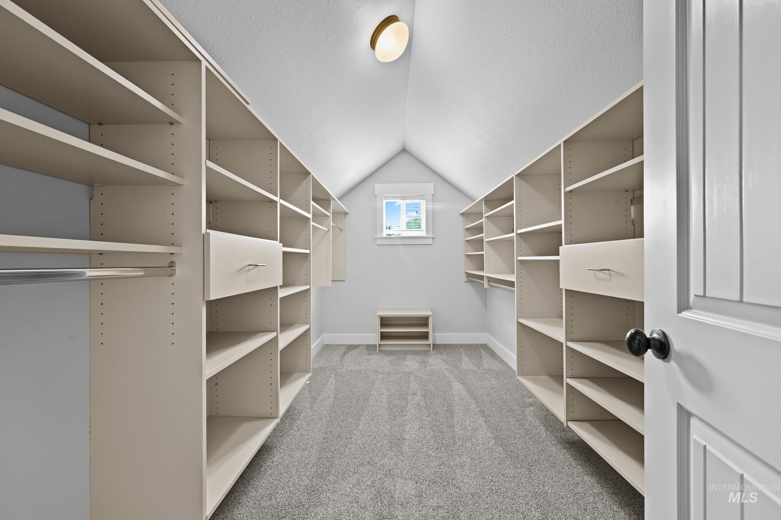 Walk in closet with lofted ceiling and light carpet