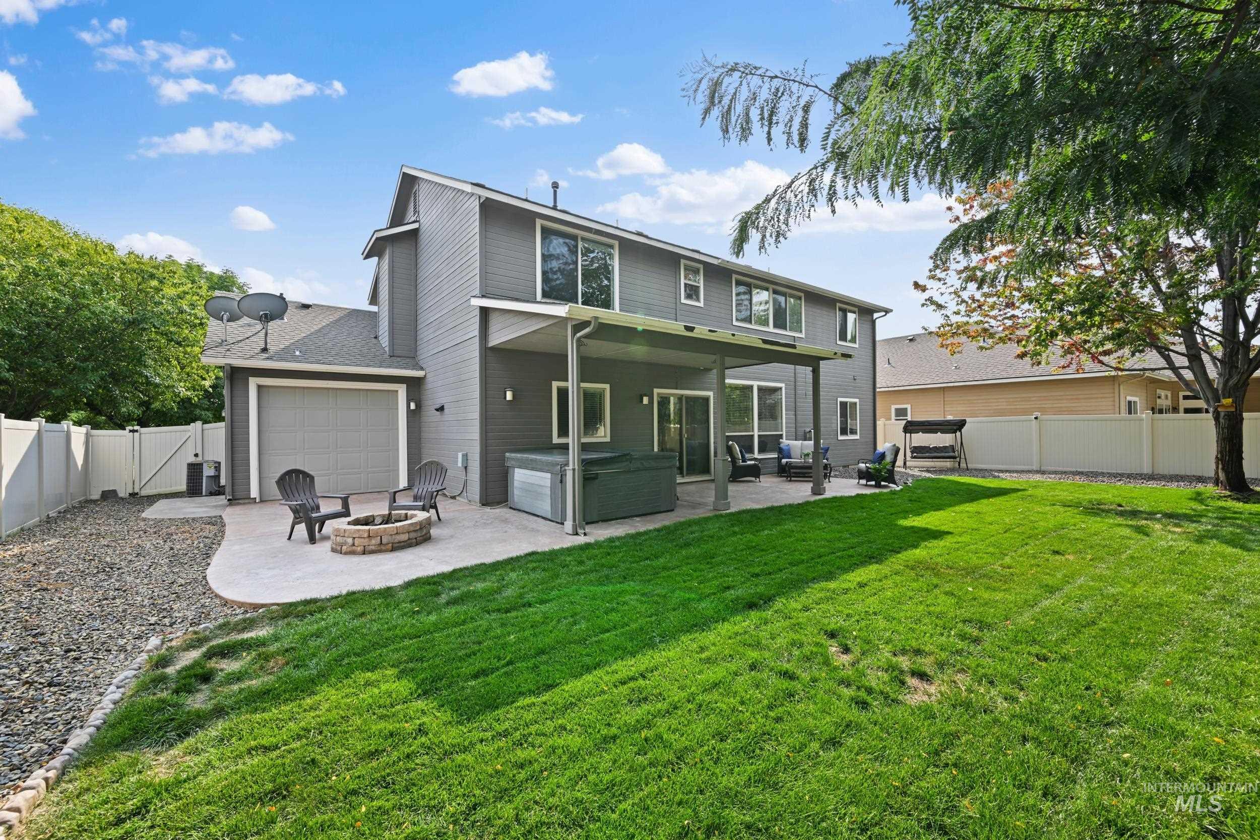 Back of house with a hot tub, a fenced backyard, a patio area, and a fire pit