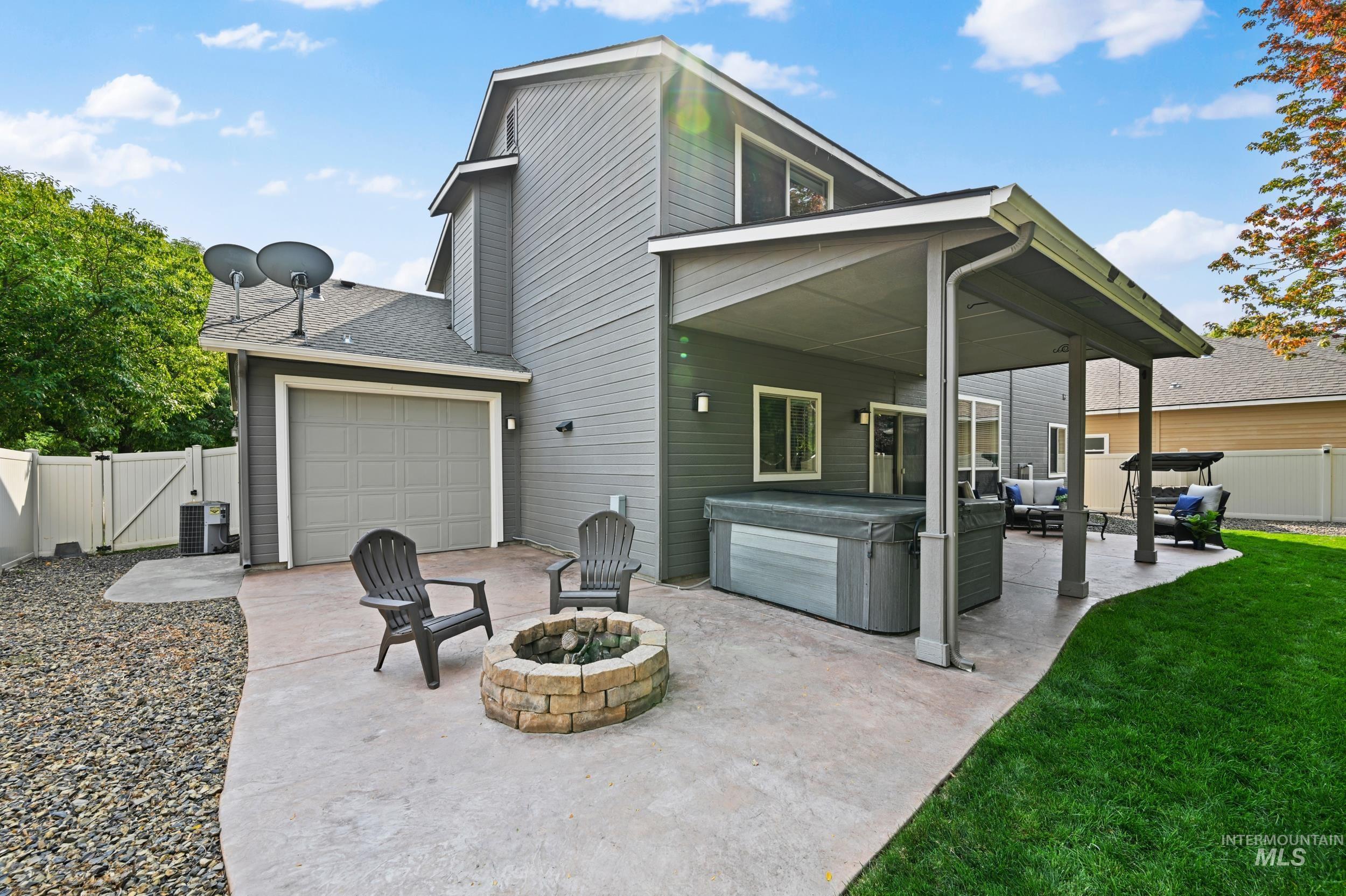 Rear view of property featuring a hot tub, a gate, a fire pit, a patio, and roof with shingles