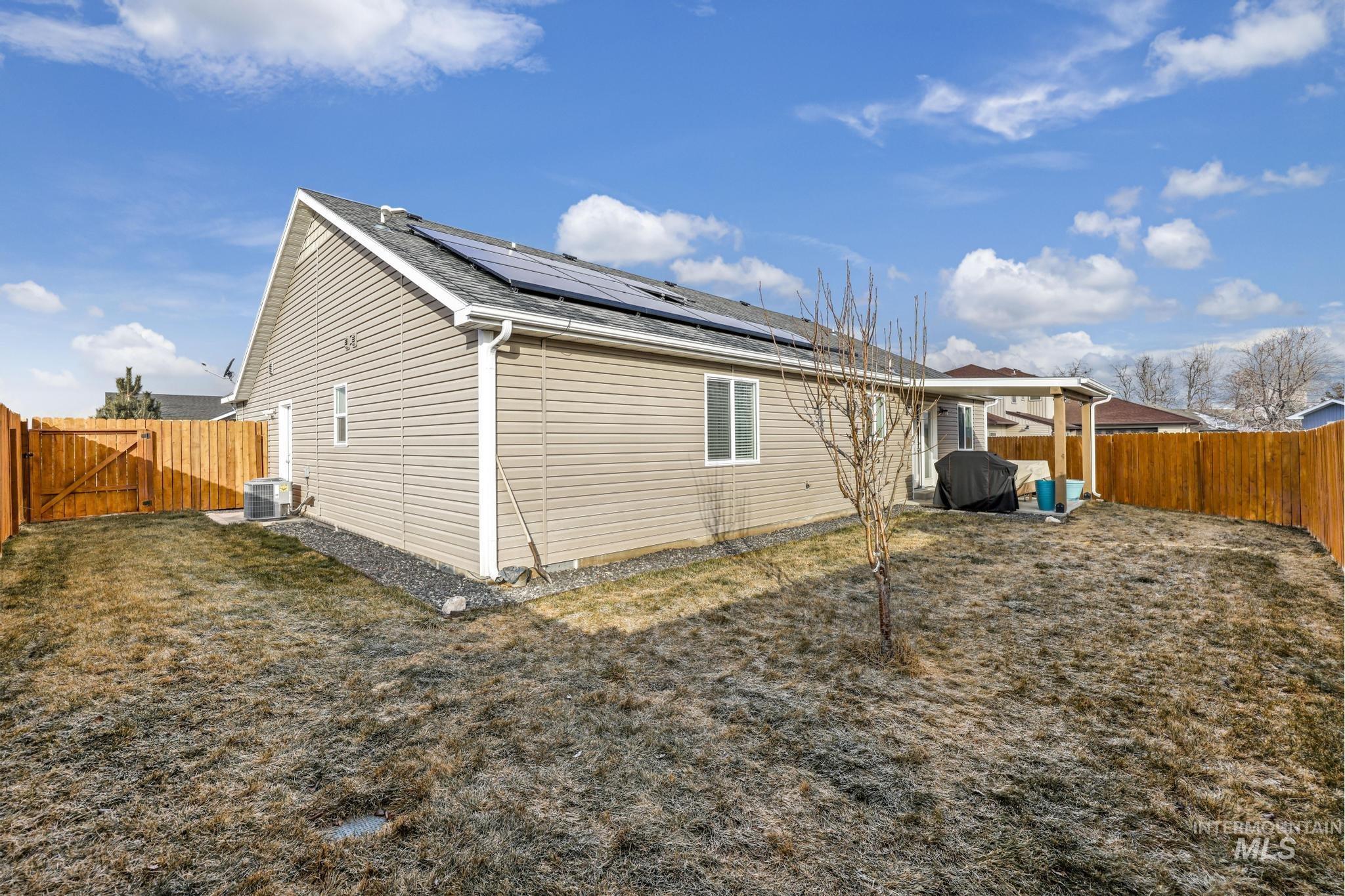 View of side of property with a gate, solar panels, a fenced backyard, and a patio area