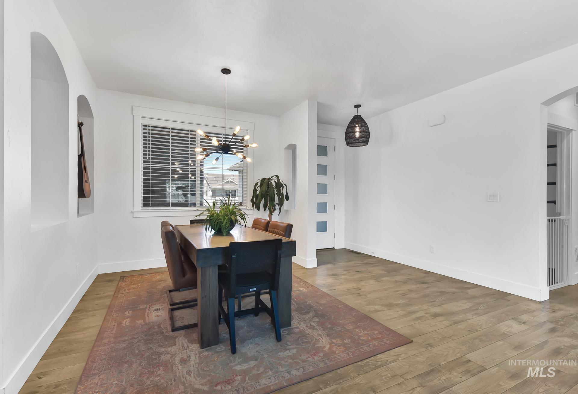 Dining area with arched walkways, wood finished floors, and a chandelier