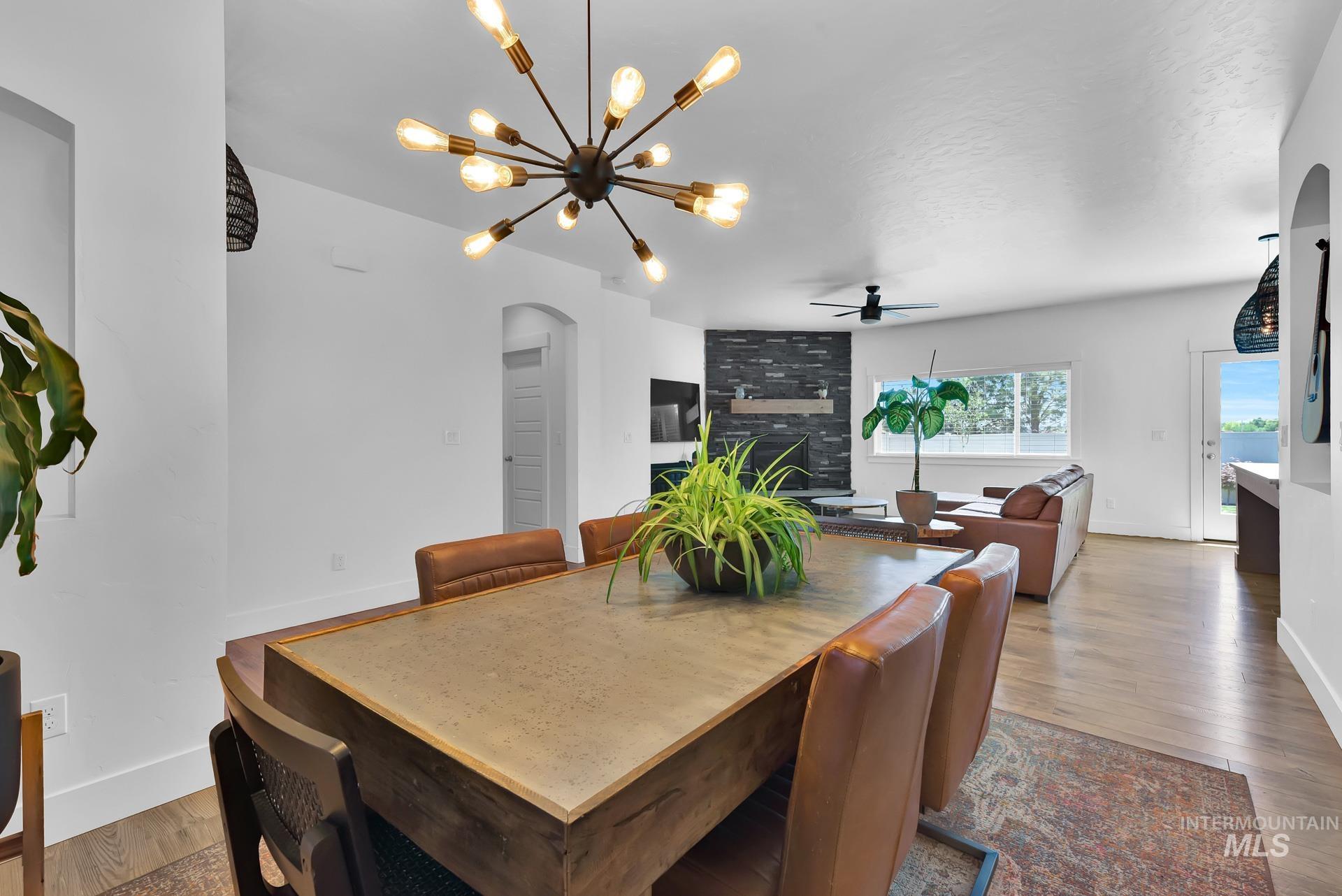 Dining room featuring arched walkways, hardwood / wood-style flooring, a fireplace, and a ceiling fan