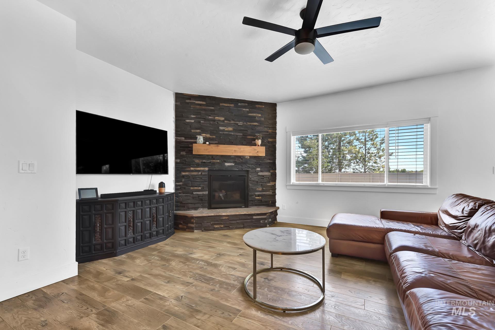 Living area featuring wood-type flooring, a fireplace, and a ceiling fan