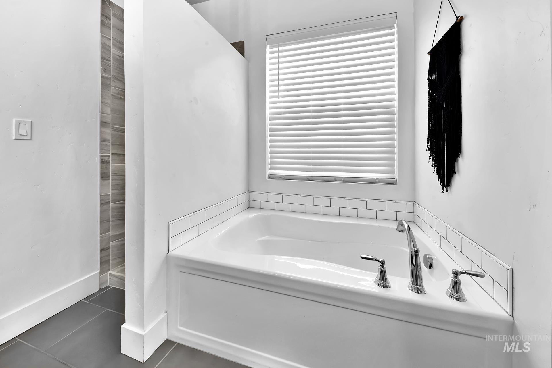 Bathroom featuring a bath and dark tile patterned flooring