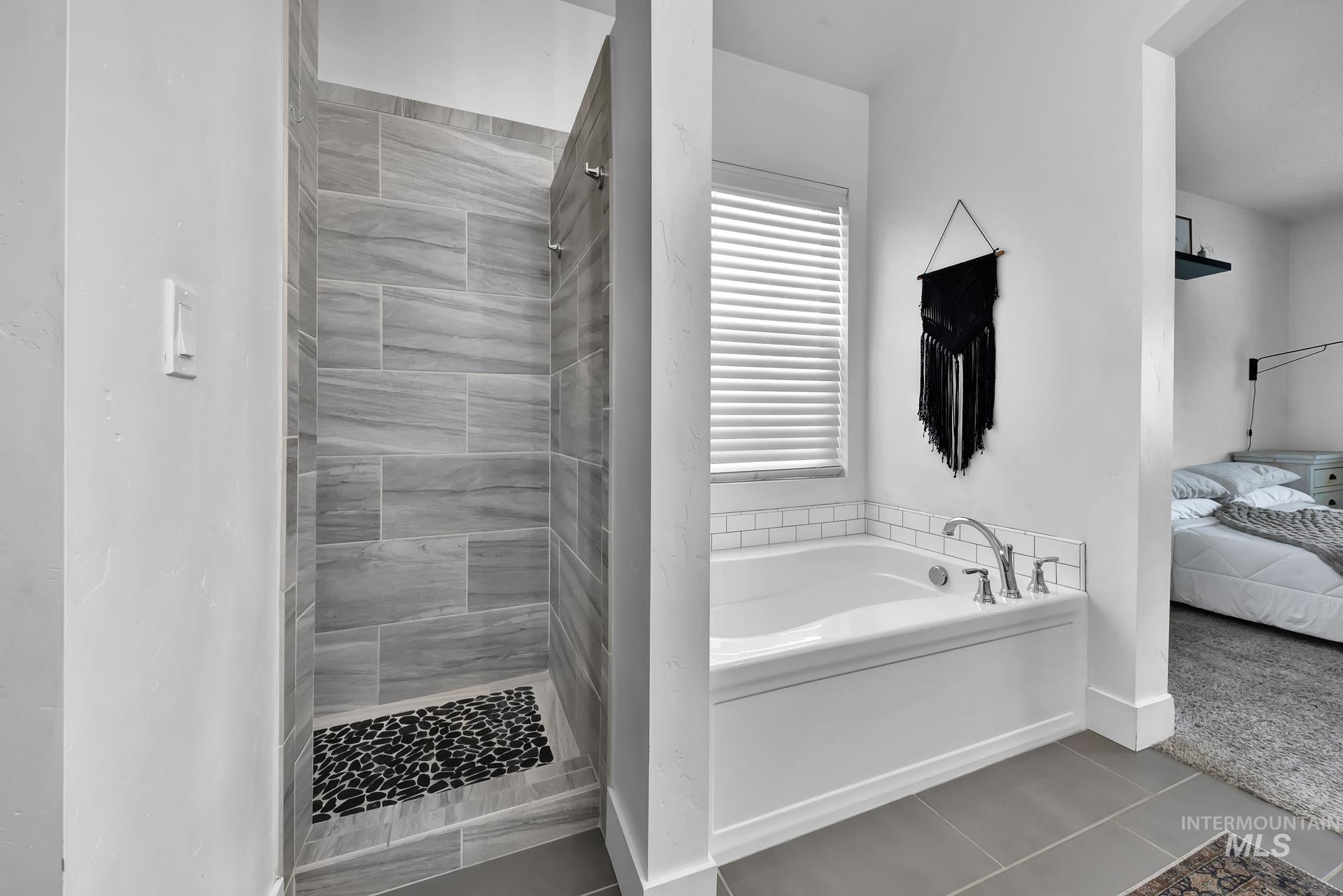 Full bath featuring a tile shower, a garden tub, ensuite bath, and tile patterned flooring